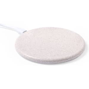 A wireless charger in a light beige colour with a round design and a connected charging cable.