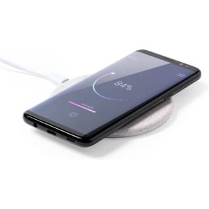 A wireless charger with a sleek design, featuring a black surface and a smartphone displaying an 84% battery charge indicator.