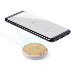 A round wireless charger with a wood and white finish, with a smartphone above displaying a charging screen.
