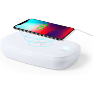 A white UV sterilizer box with a smartphone on top, featuring a wireless charging symbol illuminated.