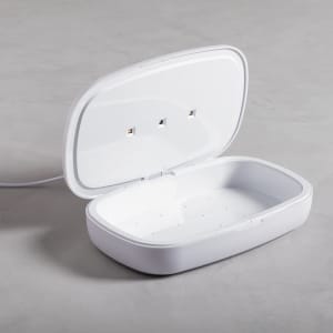 A white UV sterilizer box with a hinged lid, featuring an empty interior and three power outlets.