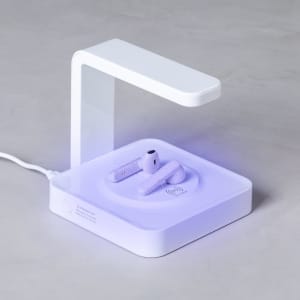 A UV sterilizer lamp in white, with a modern design, featuring wireless charging for earbuds on a square base.