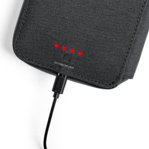 A black UV sterilizer organizer with indicators and a charging cable connected, featuring a textured surface.