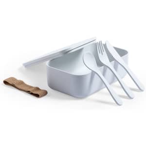 A white lunch box with a lid, accompanied by white cutlery and a brown strap.