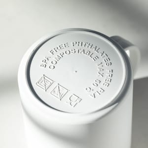 A white coffee mug with a smooth exterior and a base featuring various informative symbols and text.