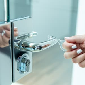 A clear anti-contact keyring being used to open a shiny door handle. The handle is silver with a keyhole.