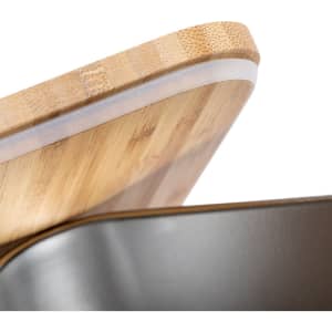 A bamboo lid with a smooth edge fitted on a metal lunch box, showcasing a sleek design and natural materials.
