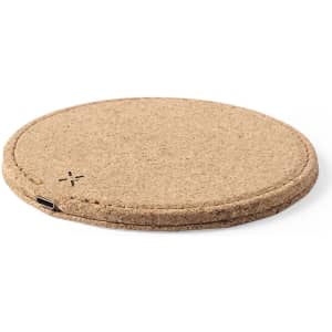 A round wireless charger in a natural cork finish, featuring a USB-C port and a simple branding logo.