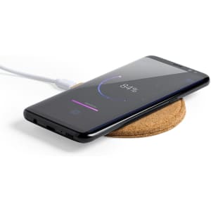 A wireless charger with a cork base, featuring a smartphone charging on it, displaying a battery percentage on the screen.