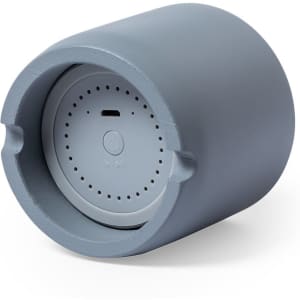 A cylindrical grey speaker with a textured surface and a round base featuring a control button and port.