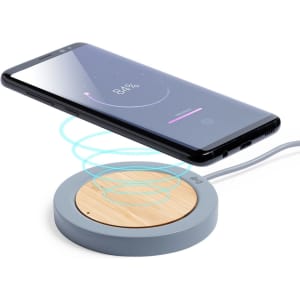 A wireless charger with a bamboo surface and grey circular base, displaying a smartphone above it, indicating charging.