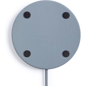 A wireless charger in a light grey colour with four black rubber feet and a connected cable. It has a simple, round design.