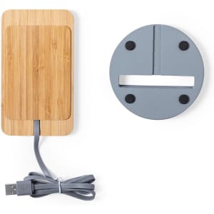 A wireless charger with a bamboo surface and grey base, featuring a USB cable for connectivity.