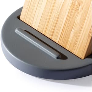 A wireless charger with a grey base and a bamboo charging surface, featuring a simple branding logo.