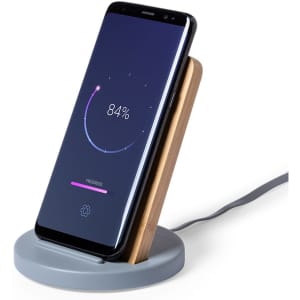 A wireless charger with a grey base and wooden support, holding a smartphone displaying a charging progress indicator.