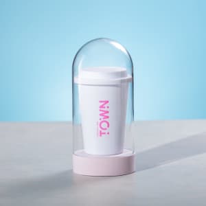 A white antibacterial cup displayed in a clear dome with a pink base, featuring a logo on the cup.