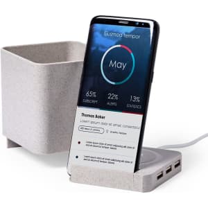 A grey multifunction pencil holder with a smartphone in a charging dock beside it, featuring multiple USB ports.