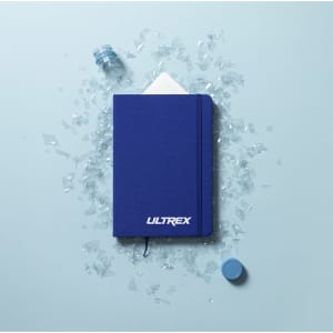 A blue notepad with a logo, surrounded by fragments of glass and a bottle cap.