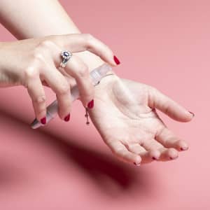 A hand using a multifunction antibacterial pen, spraying a mist onto an open palm, featuring a sleek design and silver accents.