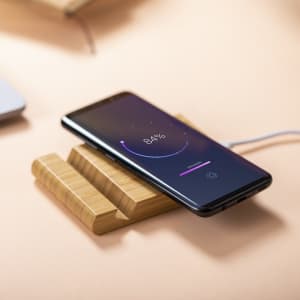 A wireless charger with a bamboo base, featuring a smartphone displaying a charging indicator.