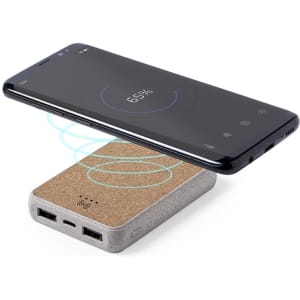 A power bank in grey with a cork surface, featuring two USB ports, and a smartphone charging wirelessly above it.