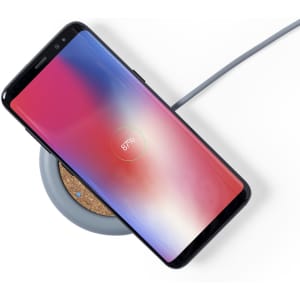 A wireless charger in grey with a smartphone charging on top, displaying a battery percentage of 87%.