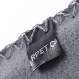 A close-up of a grey blanket with decorative stitching and a tag that includes a logo.