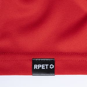 A close-up of a red polo shirt featuring a textured fabric and a tag with branding.
