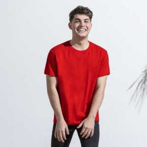 A red adult t-shirt displayed on a smiling model, featuring a simple design and casual fit. It has a logo.
