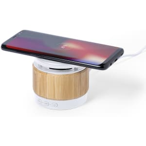 A bamboo-effect speaker charger with a black smartphone placed on top. It features a circular design and multiple buttons.