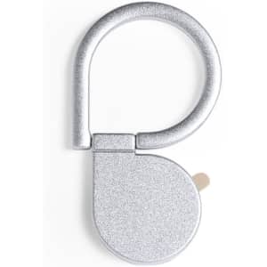 A silver, glittery phone stand with a looped top and a flat base. It features a logo on the side.