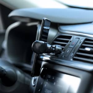 A car phone holder in black mounted on a dashboard, securely holding a smartphone.