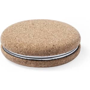 A round, beige pocket mirror with a textured surface and a thin black band around the edge.