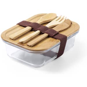 A glass lunch box with a bamboo lid and utensils, secured with a brown strap. The box is rectangular and transparent.