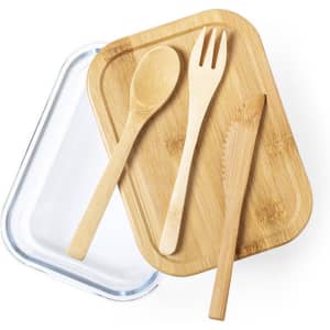 A bamboo lunch box with a glass lid, accompanied by a wooden spoon, fork, and knife on top.