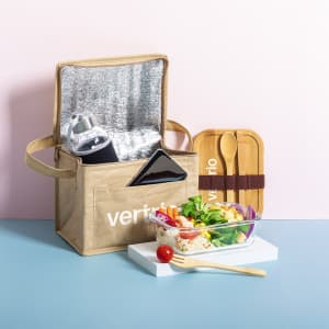 A cooler bag in beige with a logo, containing a drink bottle, phone, utensils, and a salad in a glass container.