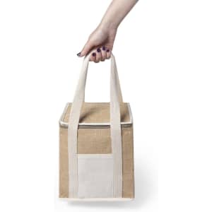 A drink bottle cooler bag in beige with white straps, featuring a front pocket and a hand holding it.