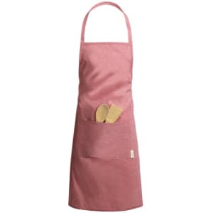 A pink apron features a front pocket with wooden cooking utensils. The apron has a logo on it.