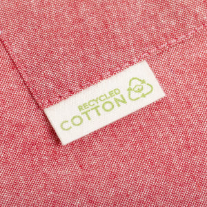 A close-up of a pink fabric with a tag that reads "Recycled Cotton" and a logo. The texture appears soft and woven.