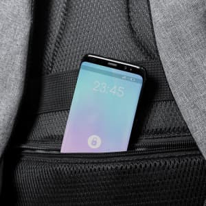 A smartphone tucked into a pocket of a grey backpack, featuring a visible screen display.