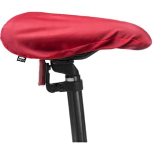 A red saddle cover fitted over a bicycle seat, secured with a black strap. It features a logo on the side.