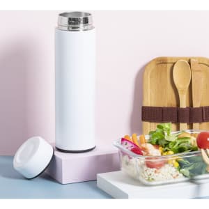 A drink bottle in white with a stainless steel lid, next to a food container and wooden utensils on a pastel background.