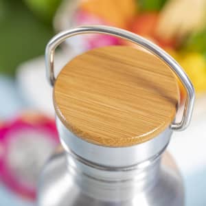 A drink bottle with a stainless steel body and a bamboo lid, featuring a metal handle.
