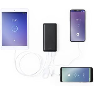 A black power bank connected to two smartphones and a tablet, with cables visible. The devices display battery status.