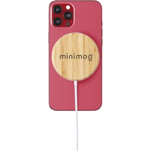 A wireless charger with a bamboo surface is positioned on a pink phone, connected by a white cable.