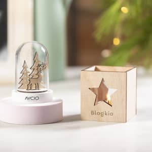 A decorative wooden candle holder with a star cut-out, next to a snow globe featuring a reindeer and trees.