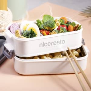 A white thermal lunch box containing pasta and a variety of vegetables, topped with a boiled egg.