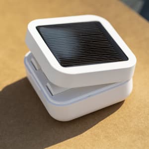 A pair of white Vinzer Earphones resting on a flat surface, featuring a sleek design with a solar panel on top.