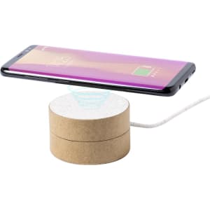 A wireless charger with a circular design in natural wood tones, featuring a smartphone displaying a charging icon above it.