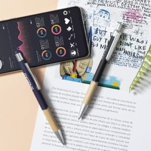 A black and blue stylus touch ball pen with a bamboo grip, resting on a sheet of paper beside a smartphone.